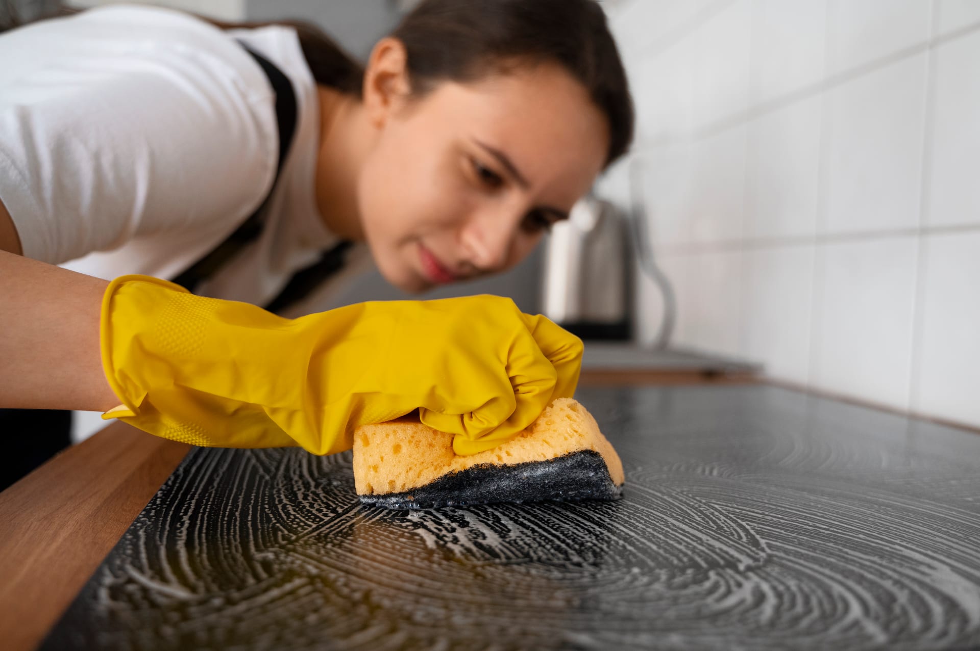 Cleaner scrubbing a kitchen surface with focused attention to detail