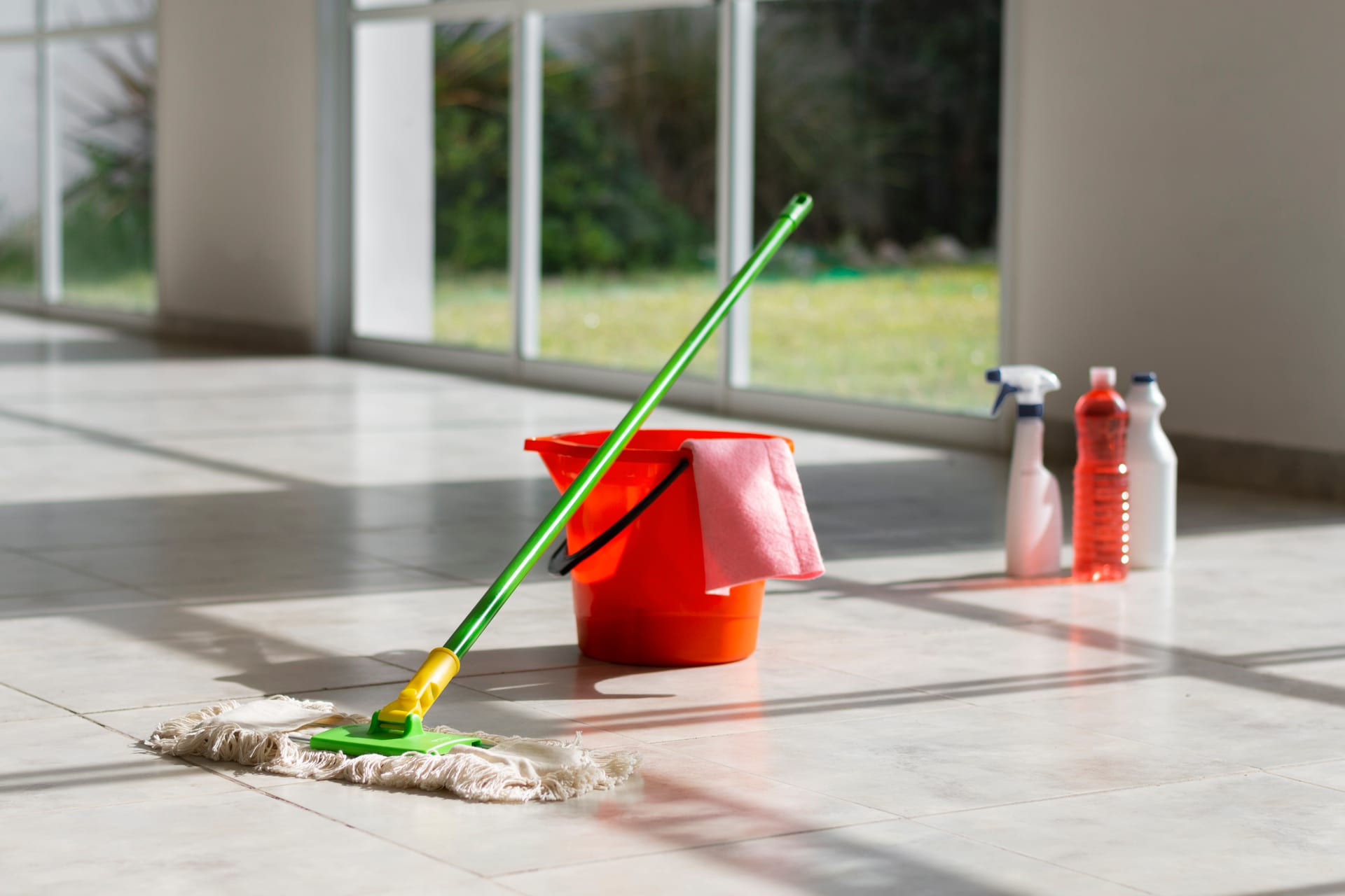 Mop, bucket, and cleaning supplies ready on a bright tile floor