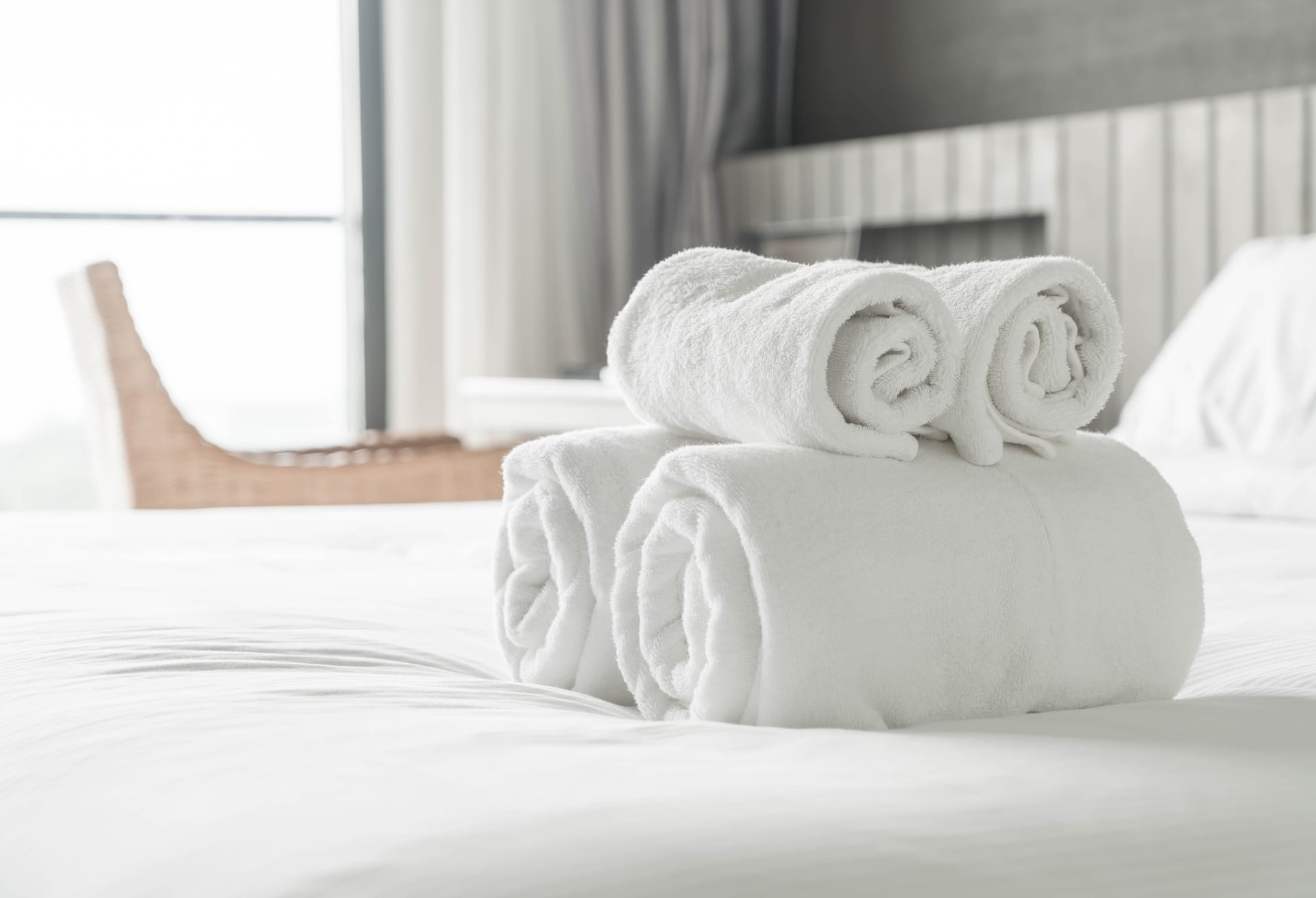 Freshly rolled white towels staged on a clean hotel-style bed